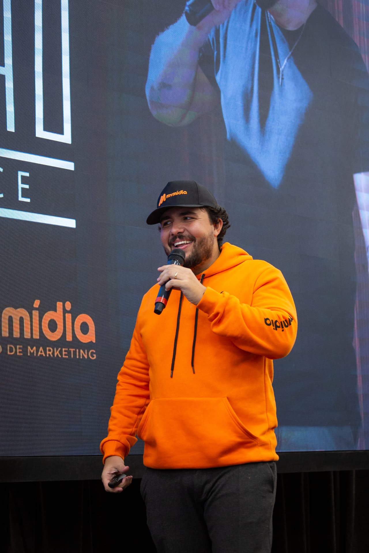 Rodrigo Duarte, Mineiro das Vendas, palestrando de moletom laranja e boné MV Mídia